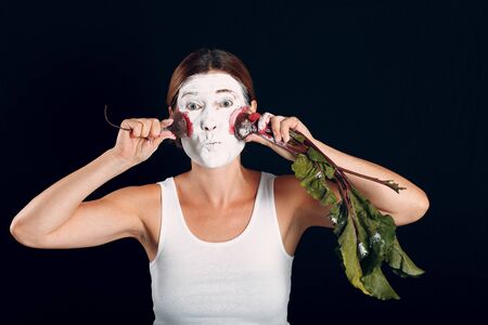 Young woman applying make-up, paints face with red  beet and makeup. How not to do make up concept.の写真素材