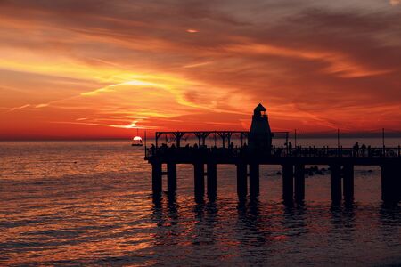 Lighthouse pier and setting sun over the waterの写真素材