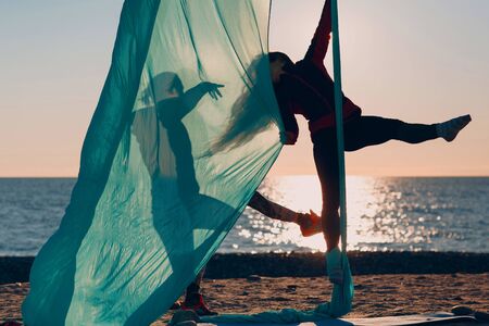 Two women practicing air yoga on the beach. Healthy Woman.