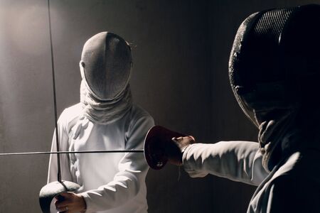 Fencer woman with fencing sword. Fencers duel concept.