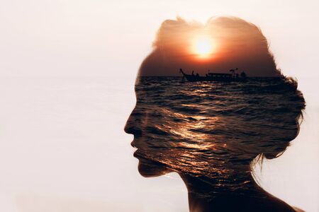 Woman with sun, boat and clouds in her headの写真素材