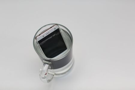 Mobile phone in vessel with waterの写真素材