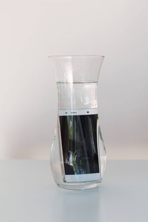 Mobile phone in vessel with waterの写真素材