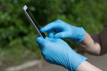 Man holds mobile phone in hands in medical gloves.の写真素材