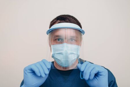 Man in face medical surgical mask with transparent shield mask and gloves.の写真素材