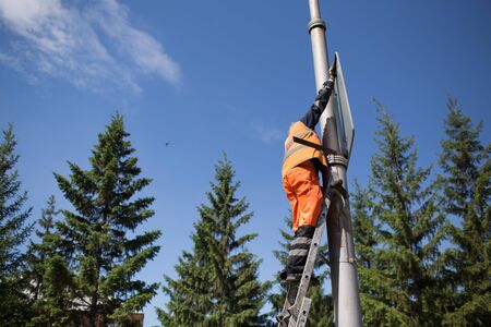 Installation road sign on pole. Road worker sets sign.の写真素材