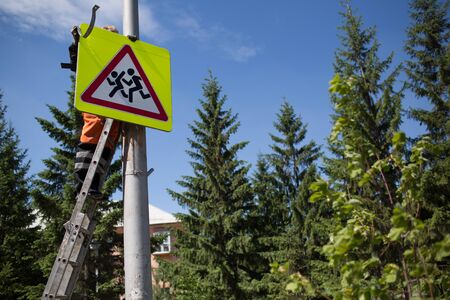 Installation road sign on pole. Road worker sets sign.の写真素材