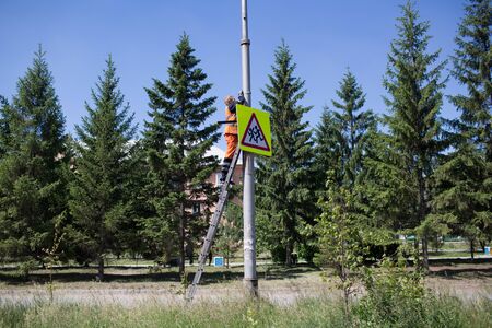 Installation road sign on pole. Road worker sets sign.の写真素材