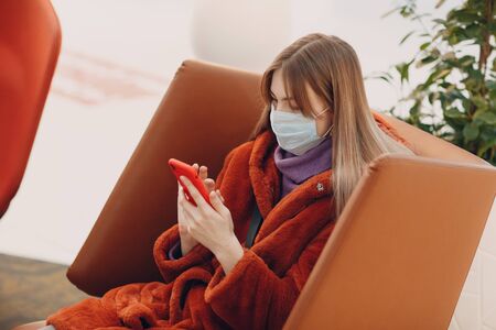 Young asian girl in medical mask with a phone.の写真素材