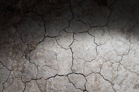 Dry cracked earth ground texture with spot light. No watering desertの写真素材