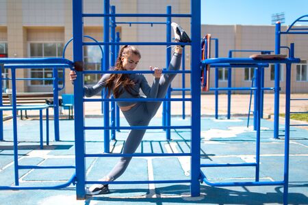 Young slim woman doing twine to stretch legs. Positive girl doing the splits outdoor.の写真素材