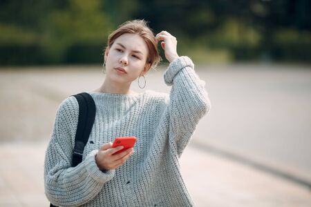 Pretty young woman with mobile phone outdoor in the park at summer.の写真素材