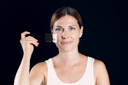Young woman applying makeup, paint face with brush.の写真素材