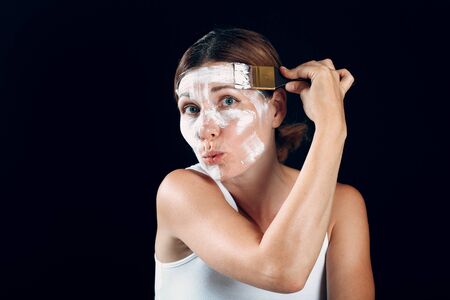 Young woman applying makeup, paint face with brush.の写真素材