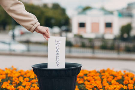 Woman throws sheet with word depression into trash can. Psychology helpの写真素材