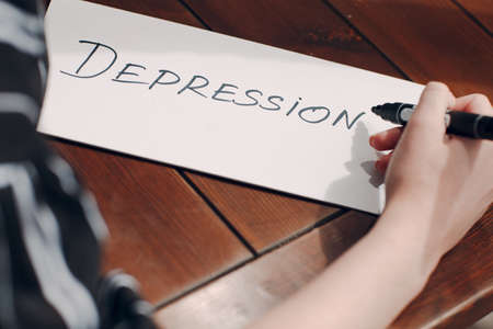 Woman hand writing word Depression on white sheet.の写真素材