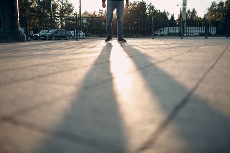 Legs and shadow of pedestrian on city street.