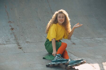 Young woman girl in green and yellow clothes going roller skateの写真素材