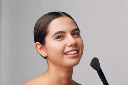 Portrait of young beautiful positive woman with nude make up and brush.の写真素材