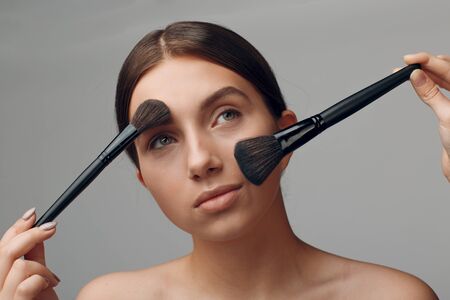 Portrait of young beautiful positive woman with nude make up and brush.の写真素材