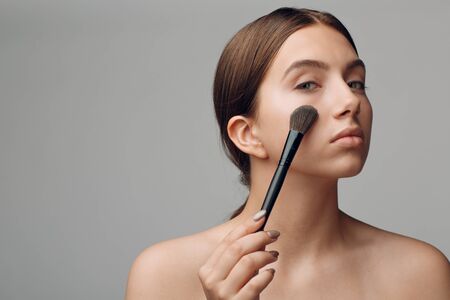 Portrait of young beautiful positive woman with nude make up and brush.の写真素材