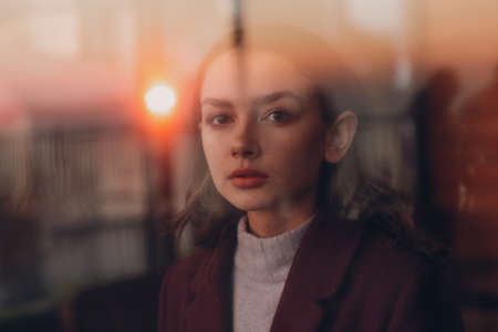 Beautiful young teenager girl portrait behind window glass