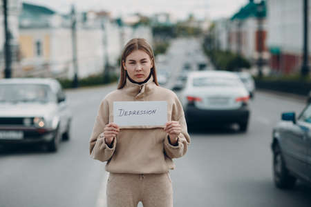 Woman holding white sheet paper labeled word Depression in hand.の写真素材