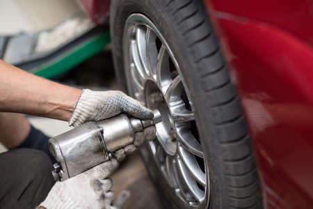 Repair or changing tire car vehicle mechanic screwing car wheel at repair service stationの写真素材