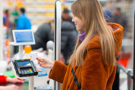 Young woman with a credit card pays for purchases at the checkout counter in the store.の写真素材
