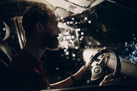 Man driver sits at steering wheel of car at night