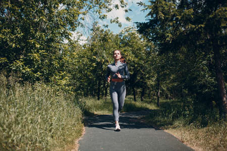 Running girl in city park. Young woman runner outdoor jogging.の写真素材