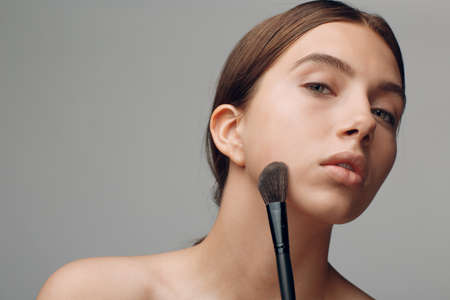 Portrait of young beautiful positive woman with nude make up and brush.の写真素材