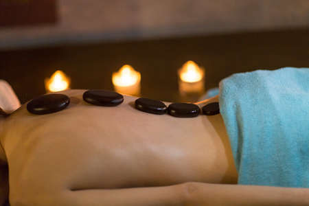 Young beautiful woman and stone massage in beauty spaの写真素材