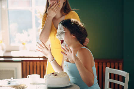 Young woman dips face in white cake with cream. Happy birthday concept.の写真素材