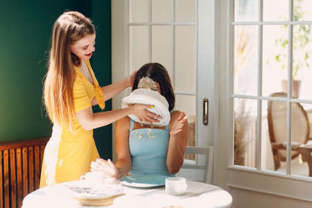 Young woman dips face in white cake with cream. Happy birthday concept.