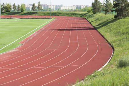 Running track and field with green grass at stadium.の写真素材