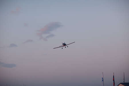 Small single engine airplane flying against sunset skyの写真素材