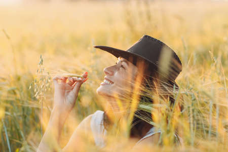 Woman farmer in cowboy hat at agricultural field on sunsetの写真素材