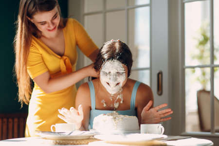 Young woman dips face in white cake with cream. Happy birthday concept.の写真素材