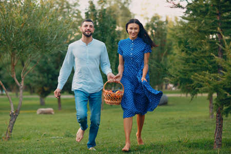 Happy Couple with Fruits in Picnic Basket Running in the Park.の写真素材