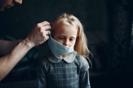 Parent helping daughter dressing uniform and put face mask preparation back to schoolの写真素材