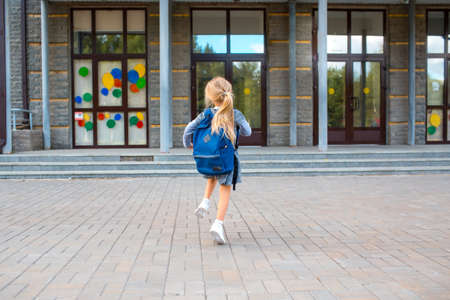 Cute little girl with backpack running back to schoolの写真素材