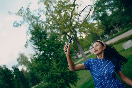 Young adult woman playing badminton in the park