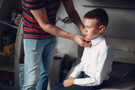 Father helping son buttoning his shirt and dressing uniform preparation back to school.の写真素材