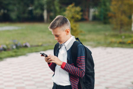 Young teenager boy with mobile phone standing at streetの写真素材