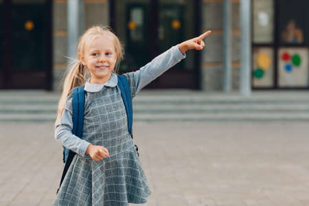Cute little girl with backpack going back to school and pointing way her fingerの写真素材