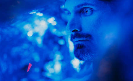Portrait of adult man with head covered by tin foil in blue lightの写真素材