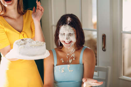 Young woman dip face in white cake with cream. Happy birthday concept.の写真素材