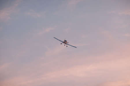 Small single engine airplane flying against sunset skyの写真素材