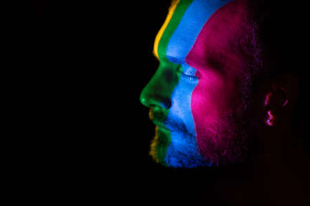 Rainbow Flag on face of adult man in dark.の写真素材